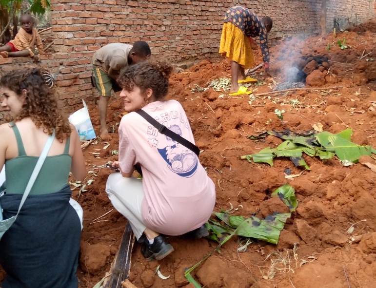 Claude, the founder of Imuhira ecotourism sitting next to a girl without shoes in a corn field